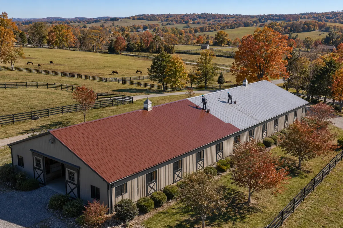 Aerial view of a long metal barn roof being coated white near Bardstown, KY
